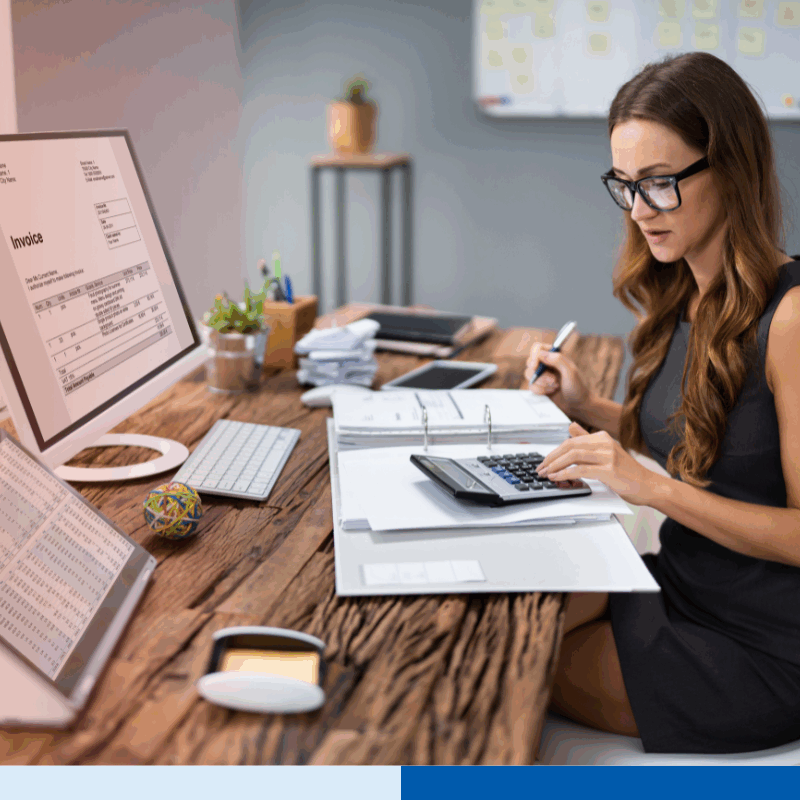 Accountant reviewing invoices and financial records on computer screens, representing services offered by remote bookkeeping companies.