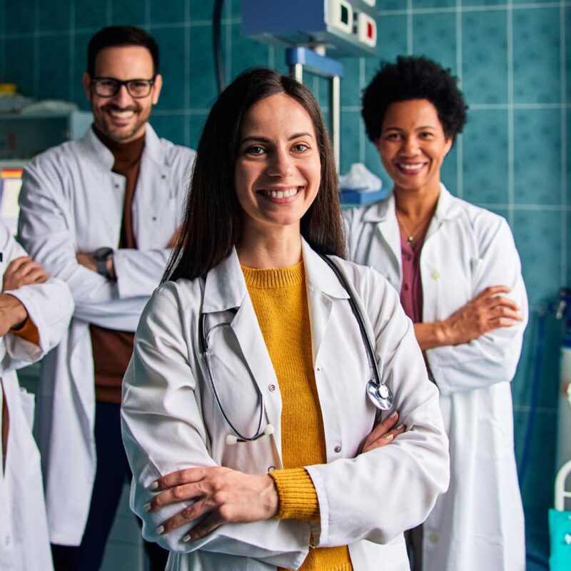 Group of smiling healthcare professionals standing together in a medical setting.