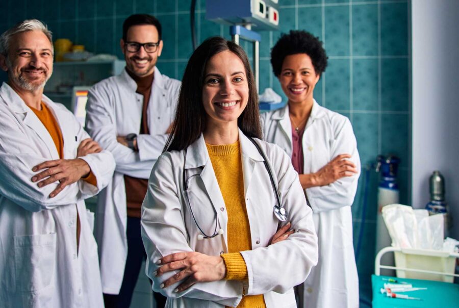Group of smiling healthcare professionals standing together in a medical setting.