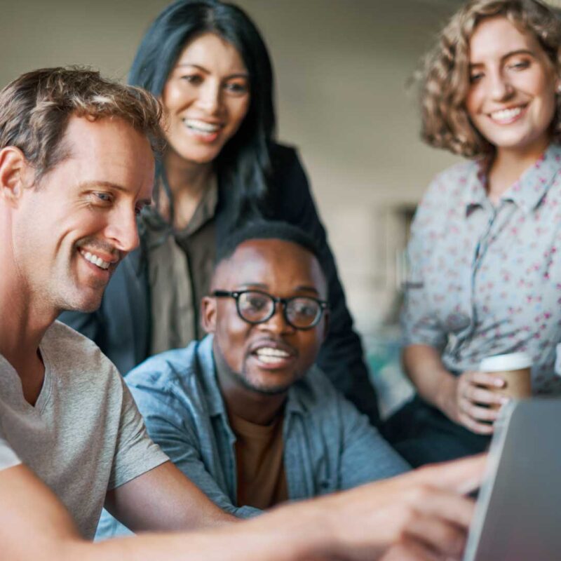 Team of software developers collaborating on a project using a laptop in a modern tech office environment.