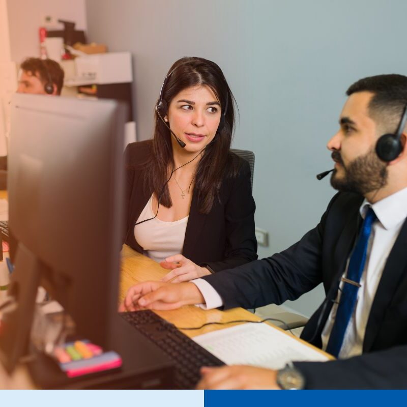 Two customer support employees taking calls and discussing